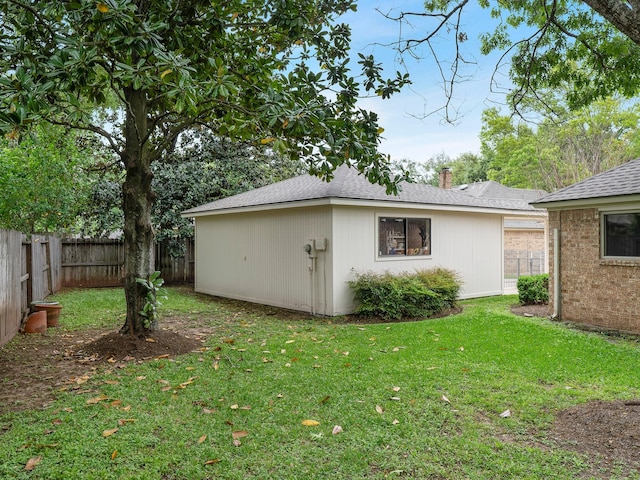 exterior space with a yard, roof with shingles, a chimney, and a fenced backyard
