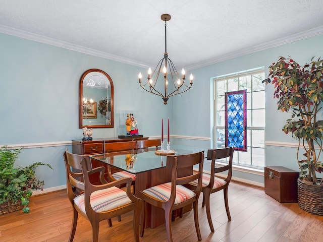 dining space with a chandelier, light wood-style flooring, a wealth of natural light, and crown molding