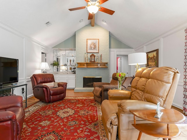 living area with visible vents, a decorative wall, lofted ceiling with beams, light wood-style flooring, and ceiling fan
