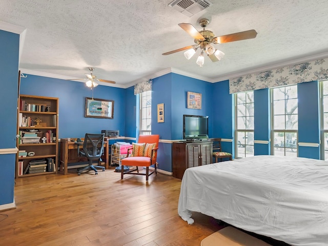 bedroom with a textured ceiling, crown molding, multiple windows, and visible vents