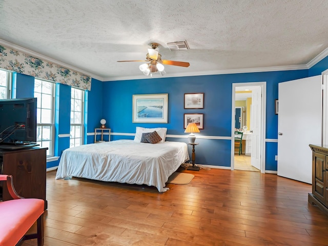 bedroom featuring a ceiling fan, a textured ceiling, hardwood / wood-style floors, ornamental molding, and visible vents