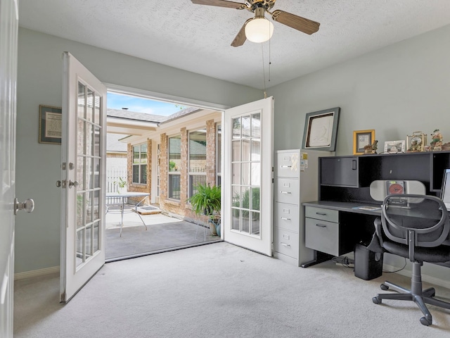 carpeted home office with a textured ceiling, ceiling fan, and french doors