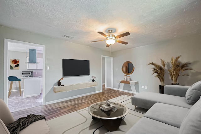 111 N 11th St, Highlands, TX 77562 - living room with wood finished floors, a ceiling fan, a textured ceiling, and baseboards