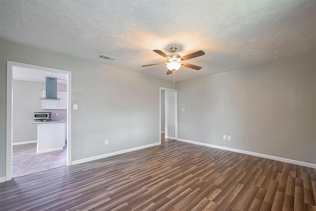 111 N 11th St, Highlands, TX 77562 - spare room featuring dark wood-type flooring, ceiling fan, baseboards, and a textured ceiling