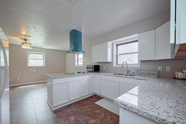 111 N 11th St, Highlands, TX 77562 - kitchen with a sink, island range hood, a peninsula, stainless steel appliances, and white cabinetry