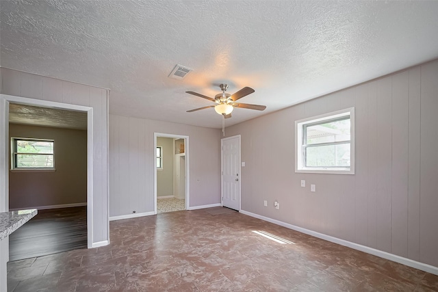 111 N 11th St, Highlands, TX 77562 - spare room with ceiling fan, a textured ceiling, baseboards, and wood walls