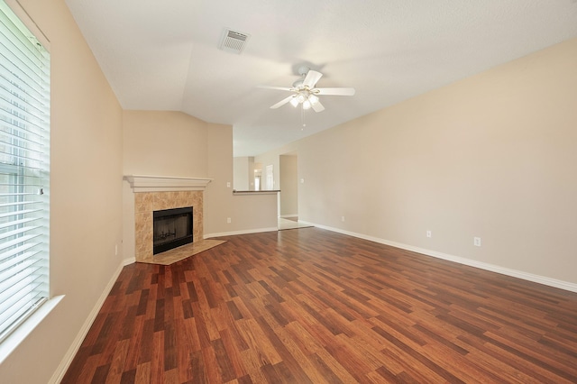 unfurnished living room with wood finished floors, ceiling fan, a tiled fireplace, baseboards, and visible vents