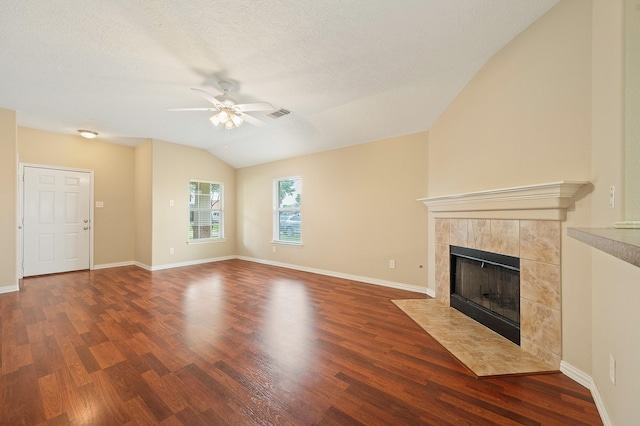 unfurnished living room with wood finished floors, ceiling fan, a tile fireplace, lofted ceiling, and visible vents