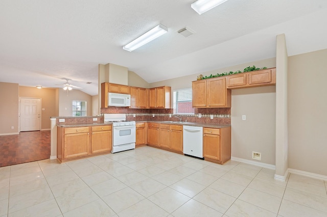 kitchen with lofted ceiling, visible vents, a sink, white appliances, and tasteful backsplash