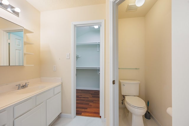 bathroom featuring toilet, vanity, visible vents, and baseboards