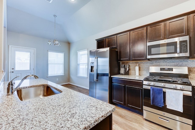 kitchen with dark brown cabinetry, a sink, light wood finished floors, appliances with stainless steel finishes, and vaulted ceiling