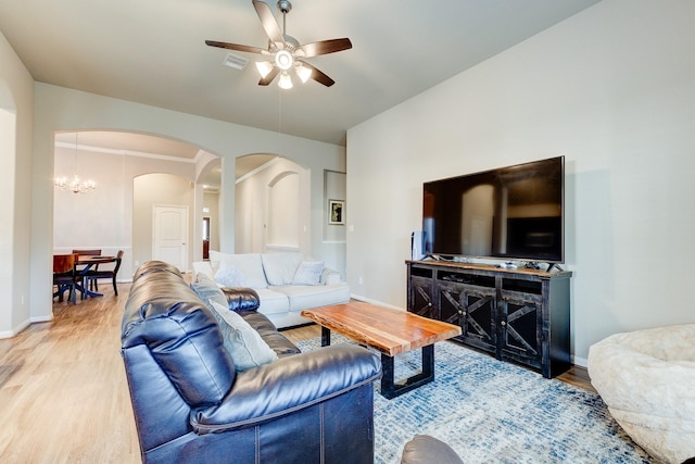 living room with visible vents, wood finished floors, baseboards, ceiling fan, and arched walkways
