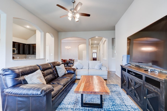 living room featuring arched walkways, ceiling fan, baseboards, and light wood-type flooring