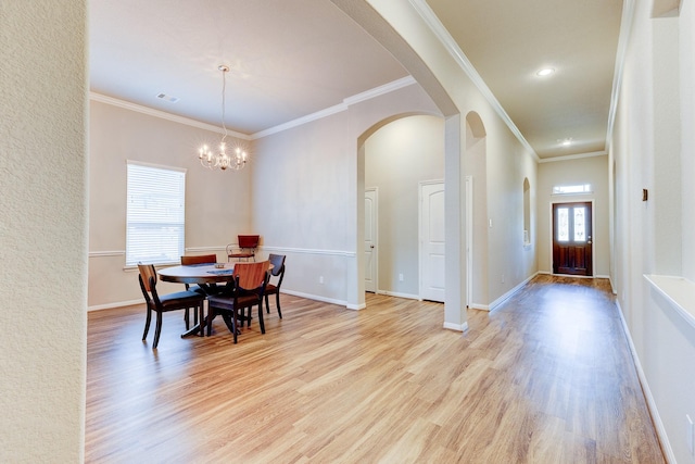dining room with crown molding, arched walkways, baseboards, an inviting chandelier, and light wood-style flooring