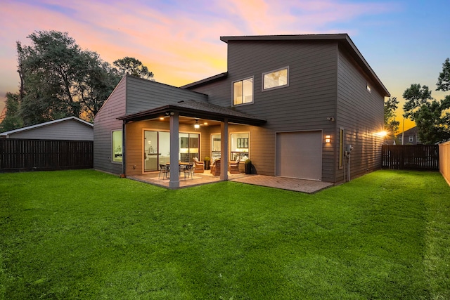 back of house with a yard, a fenced backyard, a patio area, and a garage