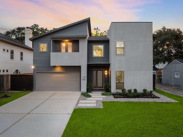 modern home featuring fence, a lawn, driveway, and a garage