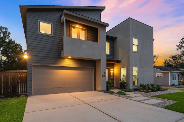 contemporary home featuring fence, driveway, and a garage