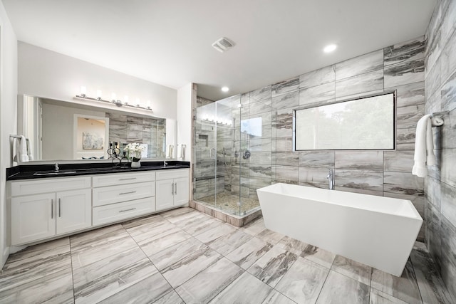 bathroom with double vanity, visible vents, a freestanding bath, a stall shower, and a sink