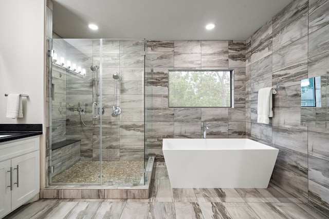 bathroom featuring vanity, recessed lighting, tile walls, a shower stall, and a soaking tub