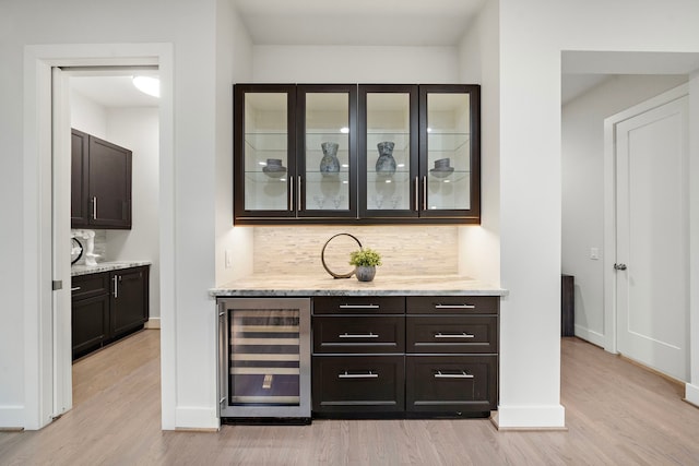 bar with light wood-style floors, baseboards, wine cooler, and tasteful backsplash