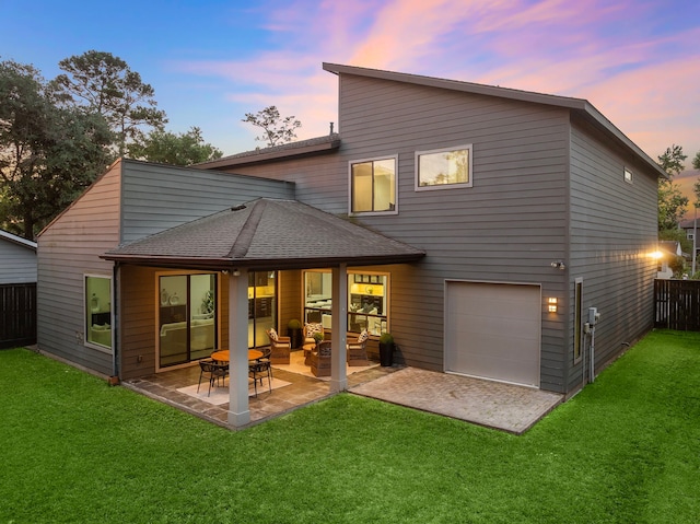 rear view of house featuring a yard, fence, a patio area, and a garage