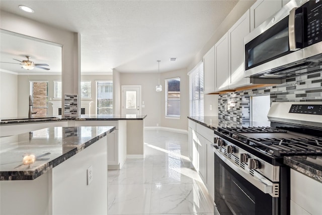 kitchen with dark stone countertops, tasteful backsplash, marble finish floor, and appliances with stainless steel finishes