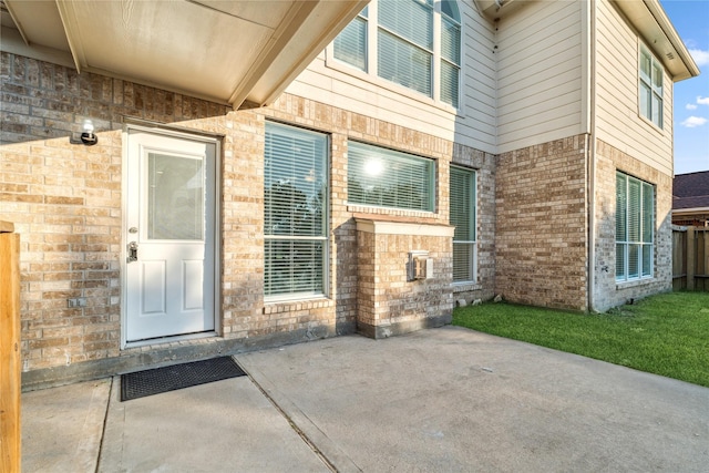 view of exterior entry featuring a patio and brick siding