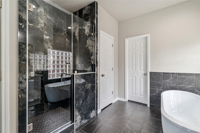 bathroom with a shower stall, a soaking tub, marble finish floor, and tile walls