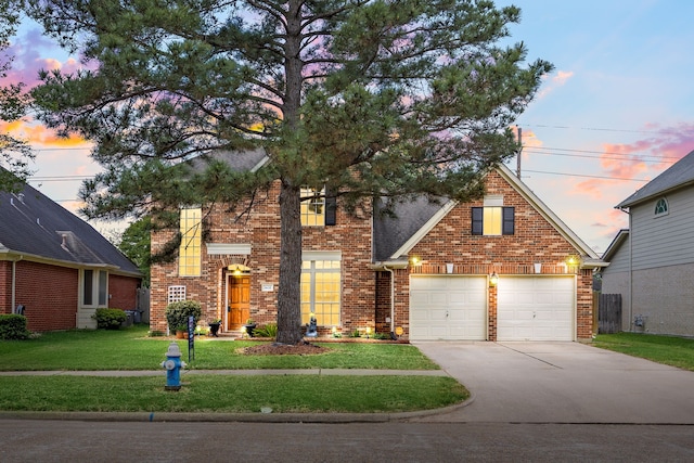 traditional-style home with a garage, a front lawn, brick siding, and concrete driveway