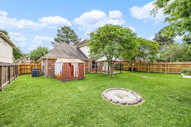 view of yard featuring an outdoor structure, a storage unit, a fenced backyard, and central AC unit