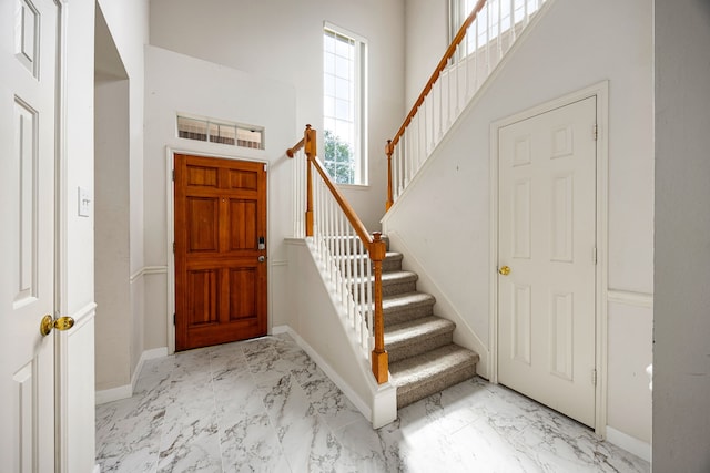 entryway with stairway, marble finish floor, and baseboards