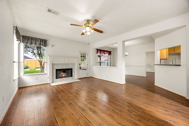 unfurnished living room featuring visible vents, a ceiling fan, baseboards, and dark wood-style flooring