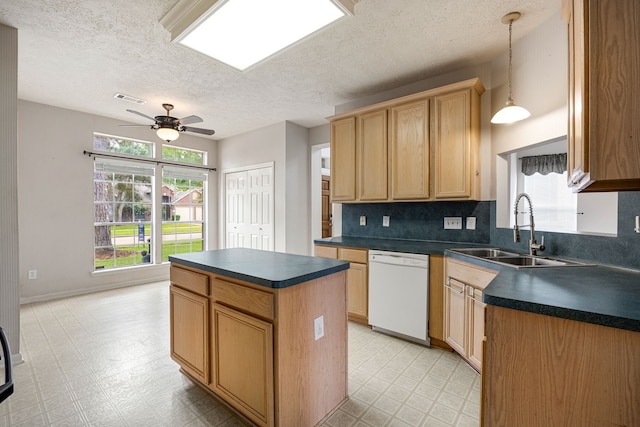 kitchen featuring light floors, dark countertops, white dishwasher, and a sink