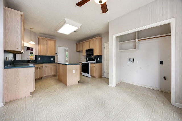 kitchen with dark countertops, black microwave, a kitchen island, gas range, and ceiling fan