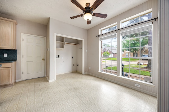 interior space featuring a textured ceiling, a ceiling fan, and baseboards