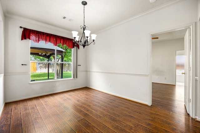 empty room with hardwood / wood-style flooring, a chandelier, baseboards, ornamental molding, and visible vents