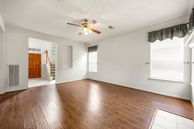 spare room with a ceiling fan, visible vents, stairs, and wood-type flooring
