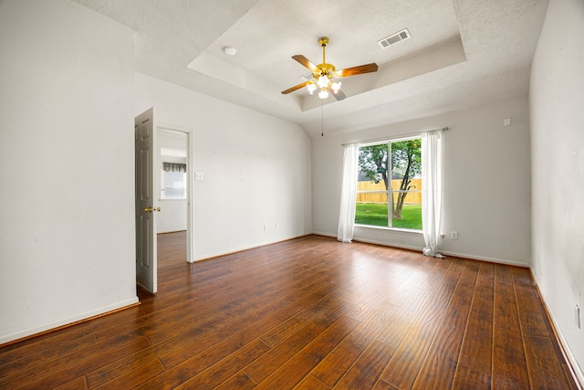 empty room featuring a tray ceiling, a textured ceiling, visible vents, ceiling fan, and hardwood / wood-style floors