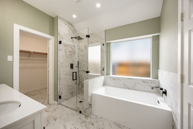 bathroom with marble finish floor, vanity, a walk in closet, a bath, and a stall shower