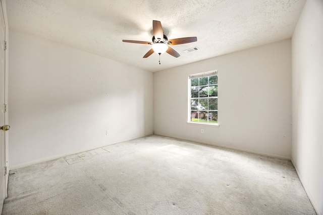 empty room featuring carpet flooring, a textured ceiling, baseboards, visible vents, and a ceiling fan