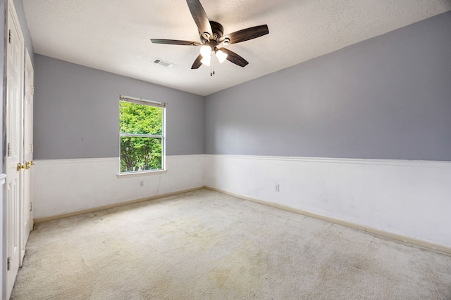 carpeted spare room with ceiling fan, baseboards, a textured ceiling, and visible vents