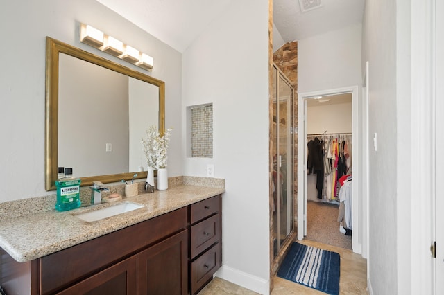 14942 Gray Ridge Dr, Houston, TX 77082 - bathroom featuring baseboards, a walk in closet, a shower stall, vanity, and vaulted ceiling