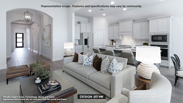 living room featuring recessed lighting, arched walkways, visible vents, and baseboards