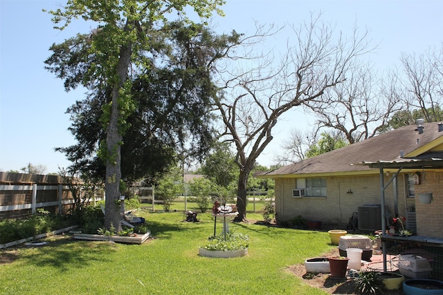 view of yard featuring central AC unit, fence, a garden, and cooling unit