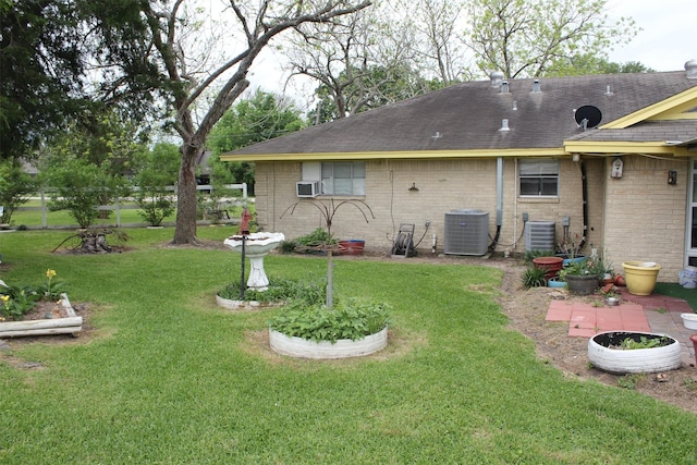 back of property featuring brick siding, a yard, central air condition unit, and a shingled roof