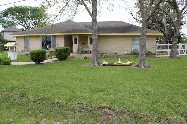 view of front facade featuring brick siding, fence, and a front yard