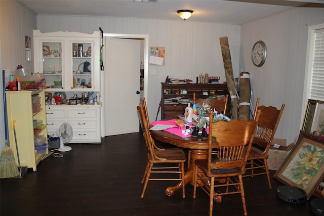 dining room with wood walls, visible vents, and dark wood-style floors