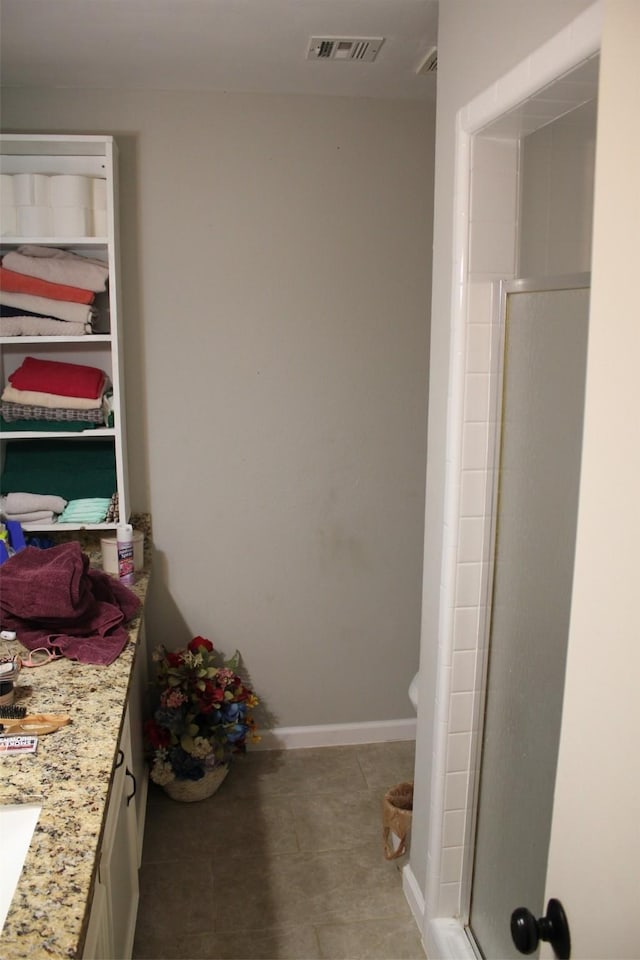 bathroom with a stall shower, baseboards, visible vents, tile patterned flooring, and vanity