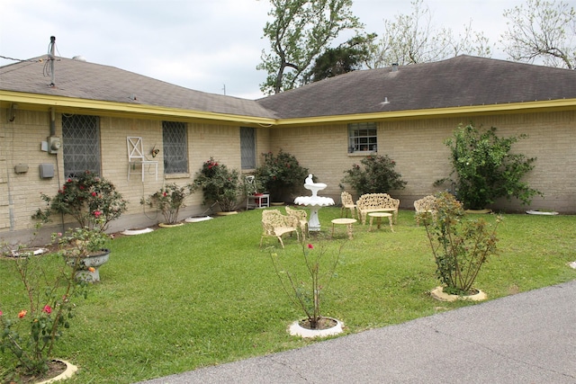 view of front of house with brick siding, roof with shingles, and a front yard