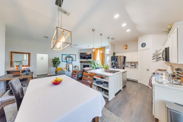 dining area featuring dark wood-style flooring, a stone fireplace, recessed lighting, visible vents, and lofted ceiling